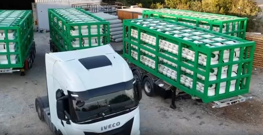 White IVECO truck with green MEGC frames loaded with CNG cylinders at facility